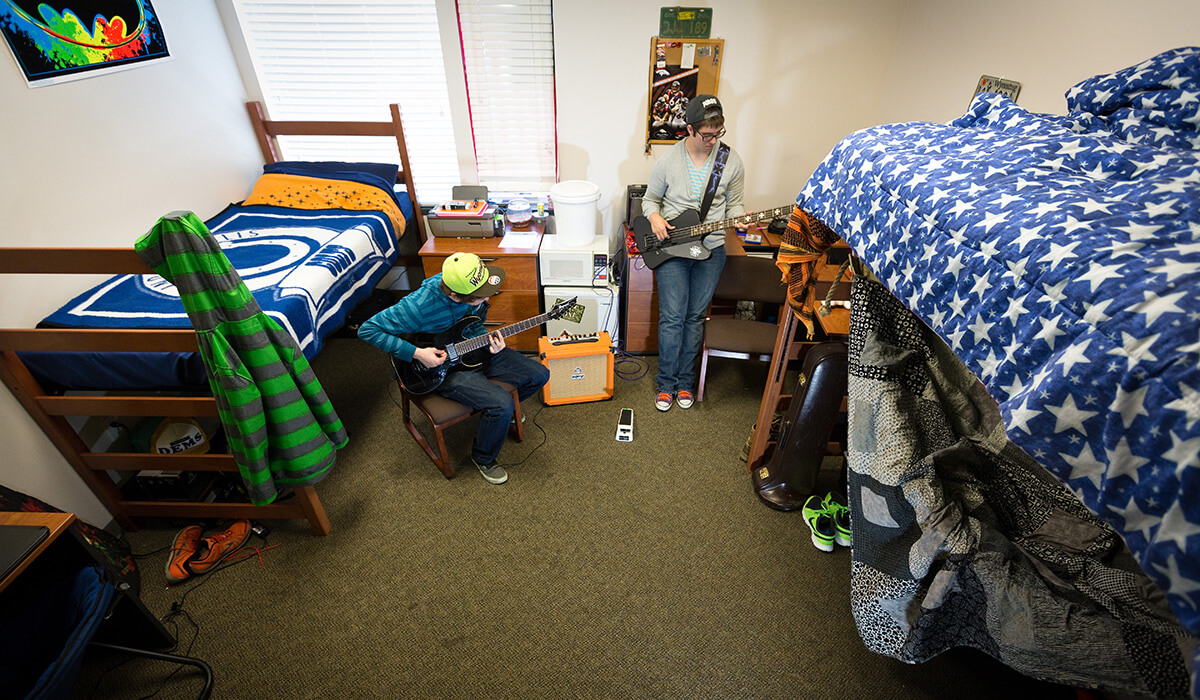 two male students in dorm room with lofted beds