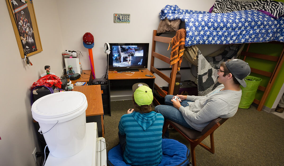 two male students playing video games in dorm room
