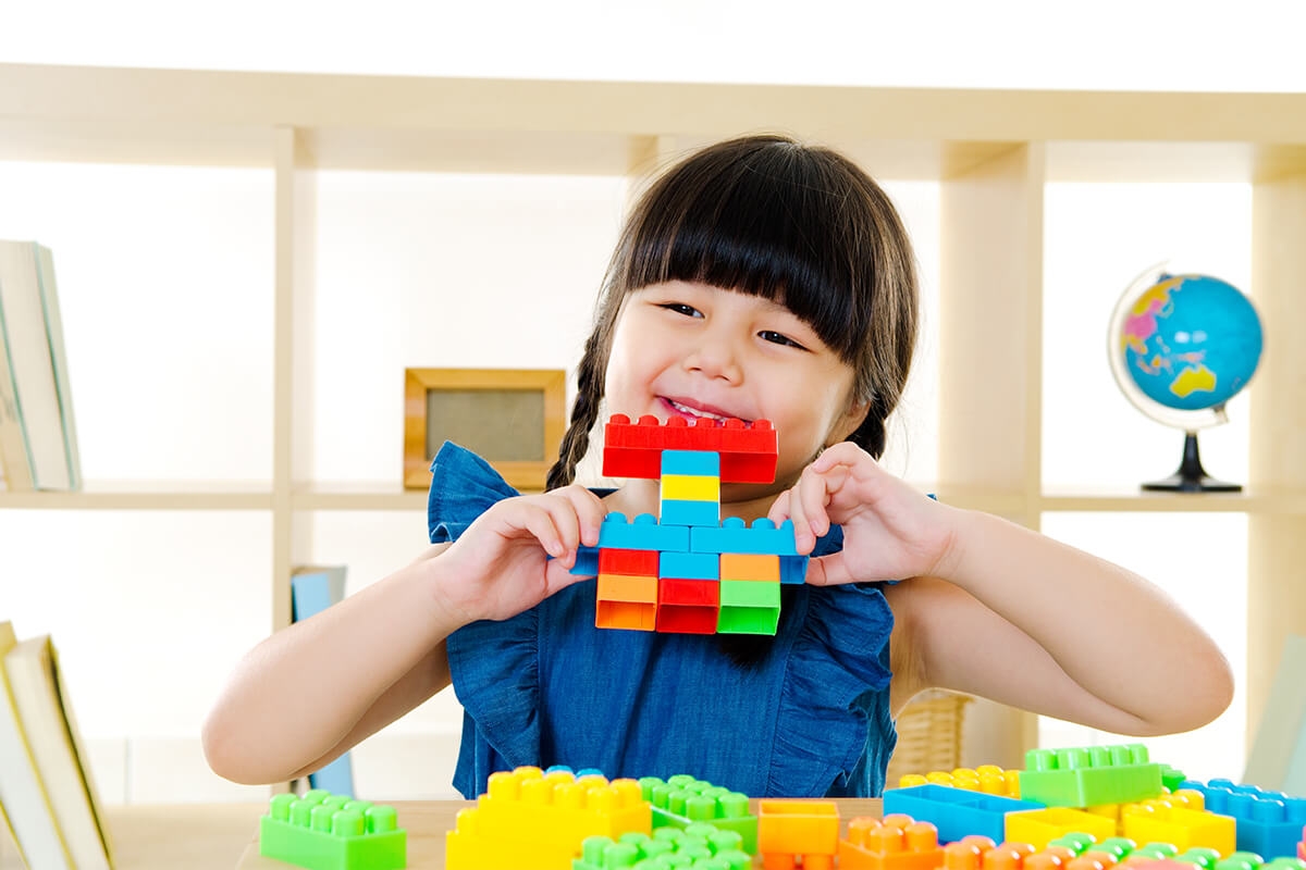 Photo of young girl with giant legos.