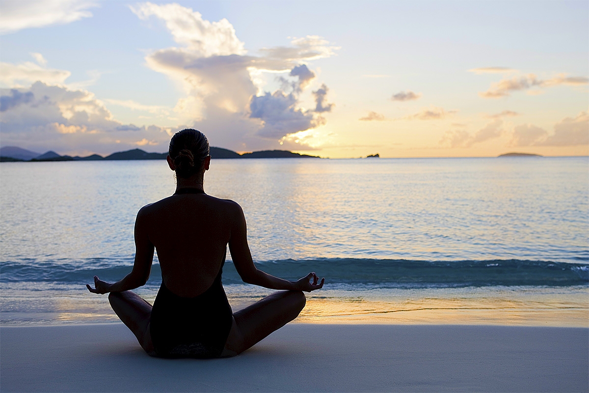 photo of person in a yoga pose at the edge of a body of water