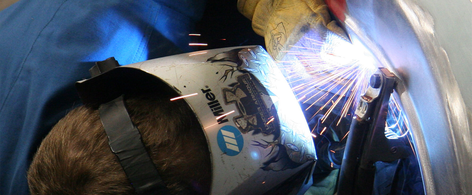 up close photo of a student wearing protective gear while working on a car
