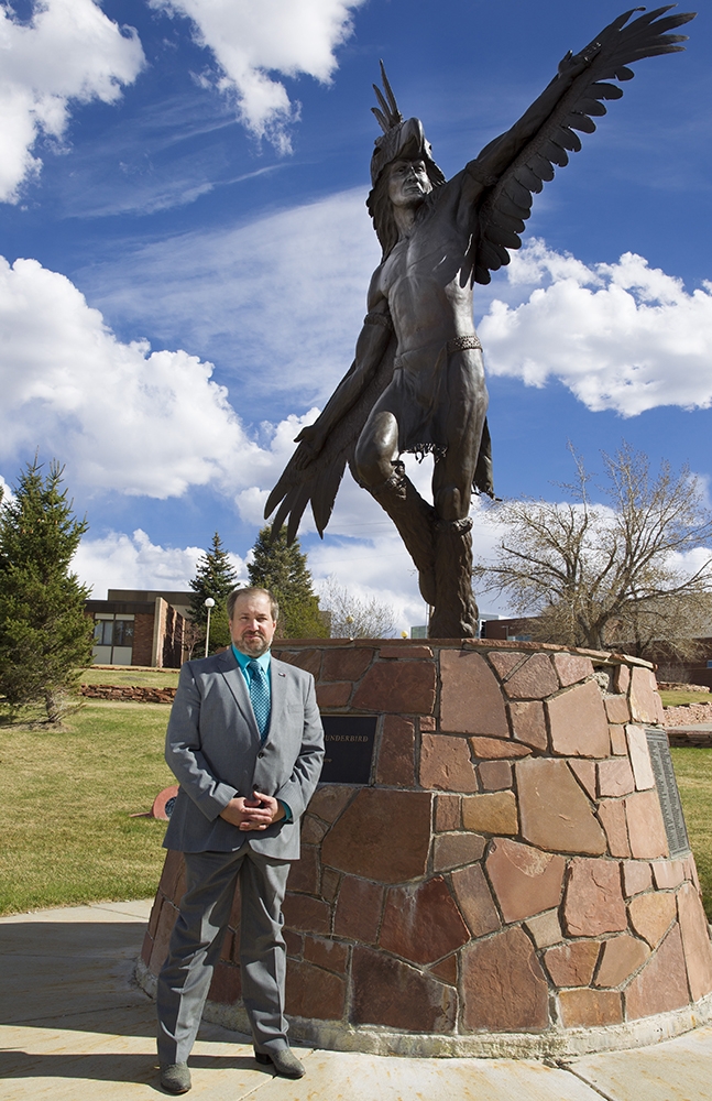 Casper College President Dr. Darren Divine in front of the Heyoka statue on campus