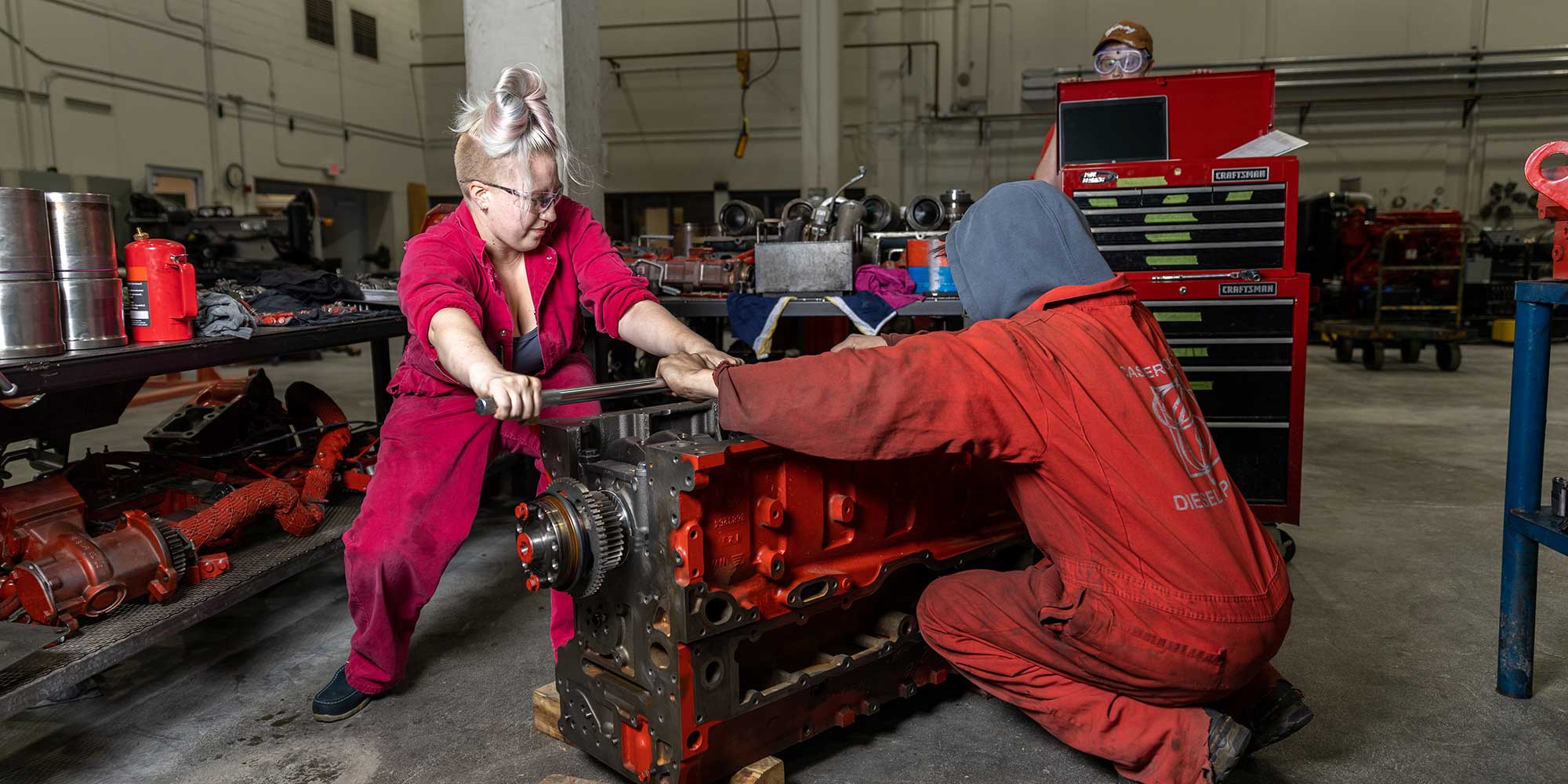 two diesel technology students working on a engine