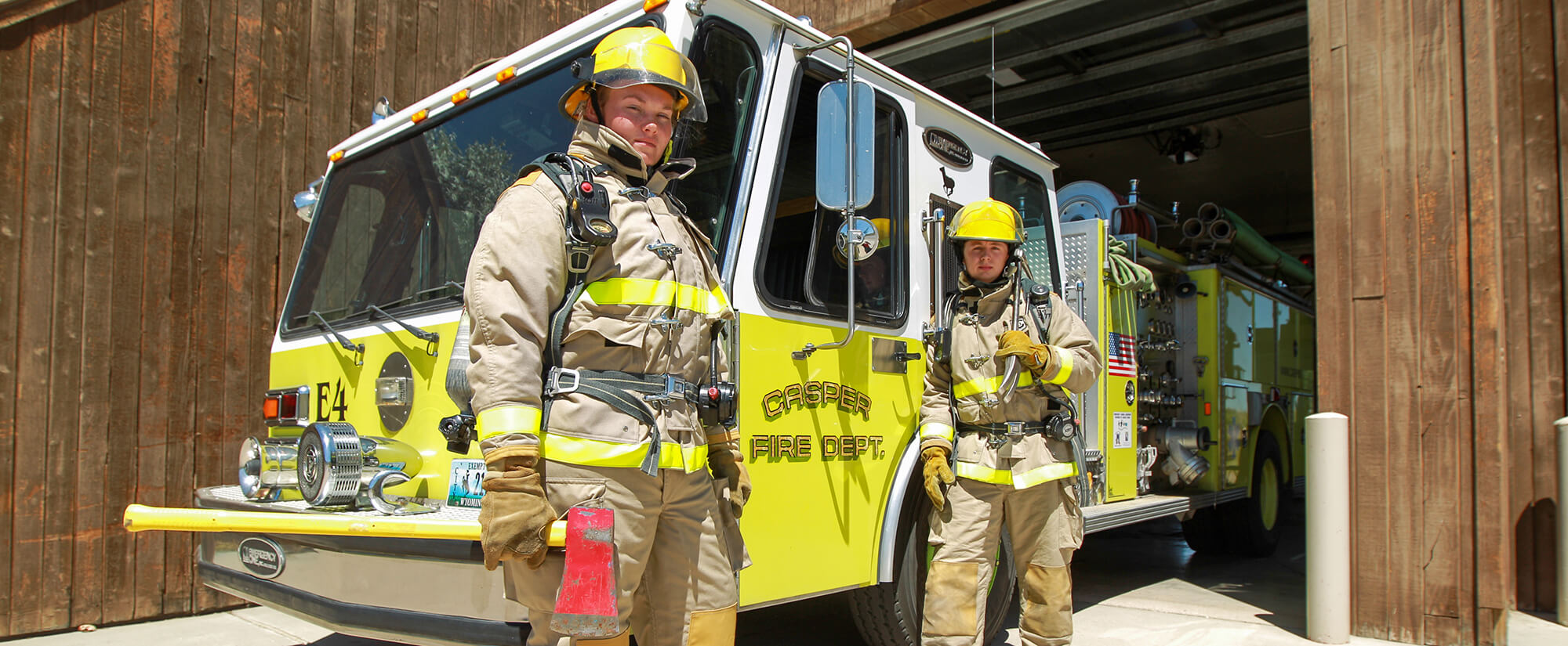 Photo of two students in firefighter gear standing in front of a fire truck at Casper College.
