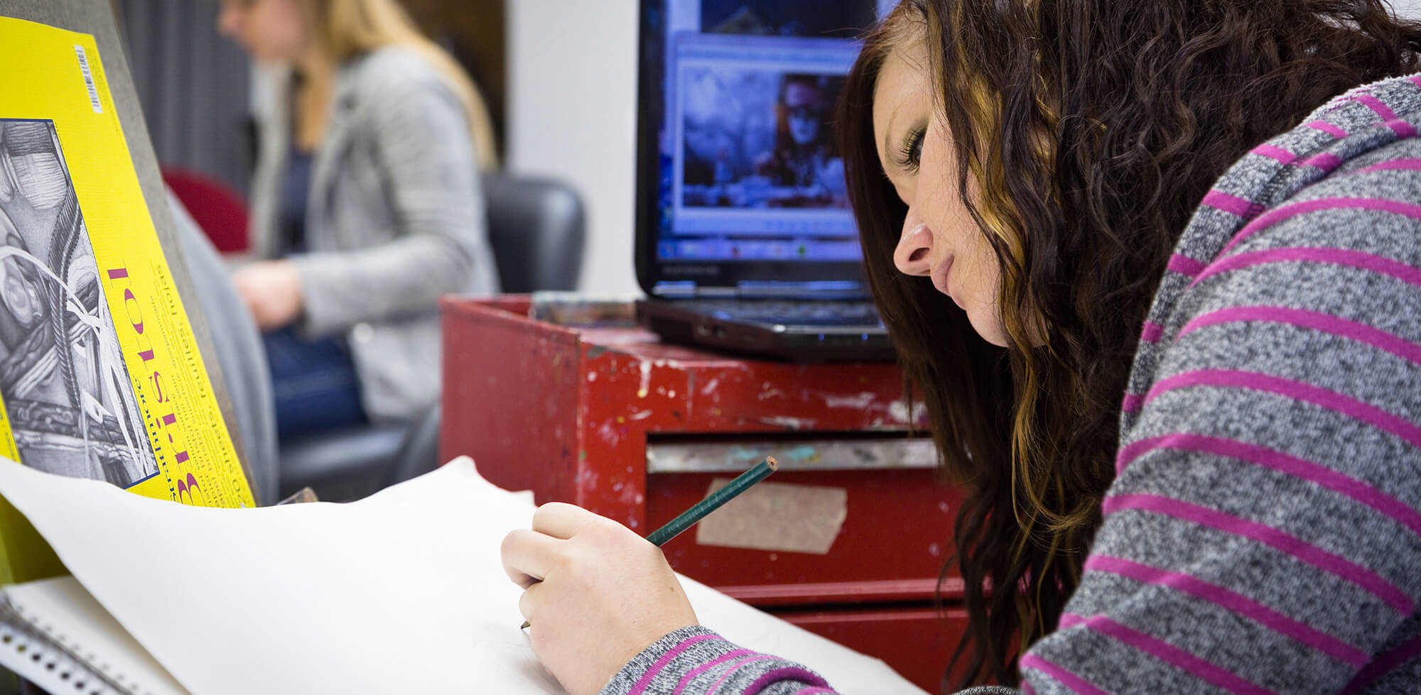 A female student focuses on drawing in a sketchbook