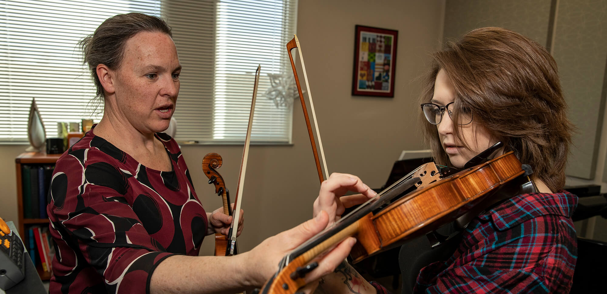 accounting-casper-college Casper College instructor gently adjust the handgrip of a student playing the violin.