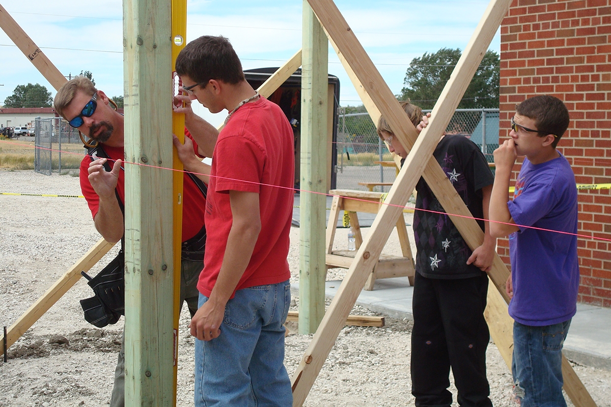 Photo of Rob Hill working with Transitions students on a post placing for a redwood and cedar pergola.