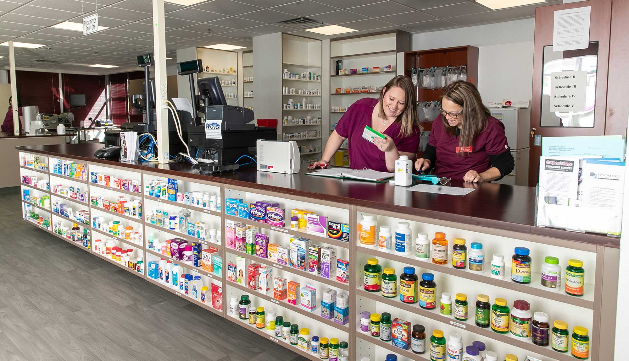 2022_10-Diesel-Technology-Program-Photos5 A student holds a pill bottle while walking past shelves set up like a pharmacy.