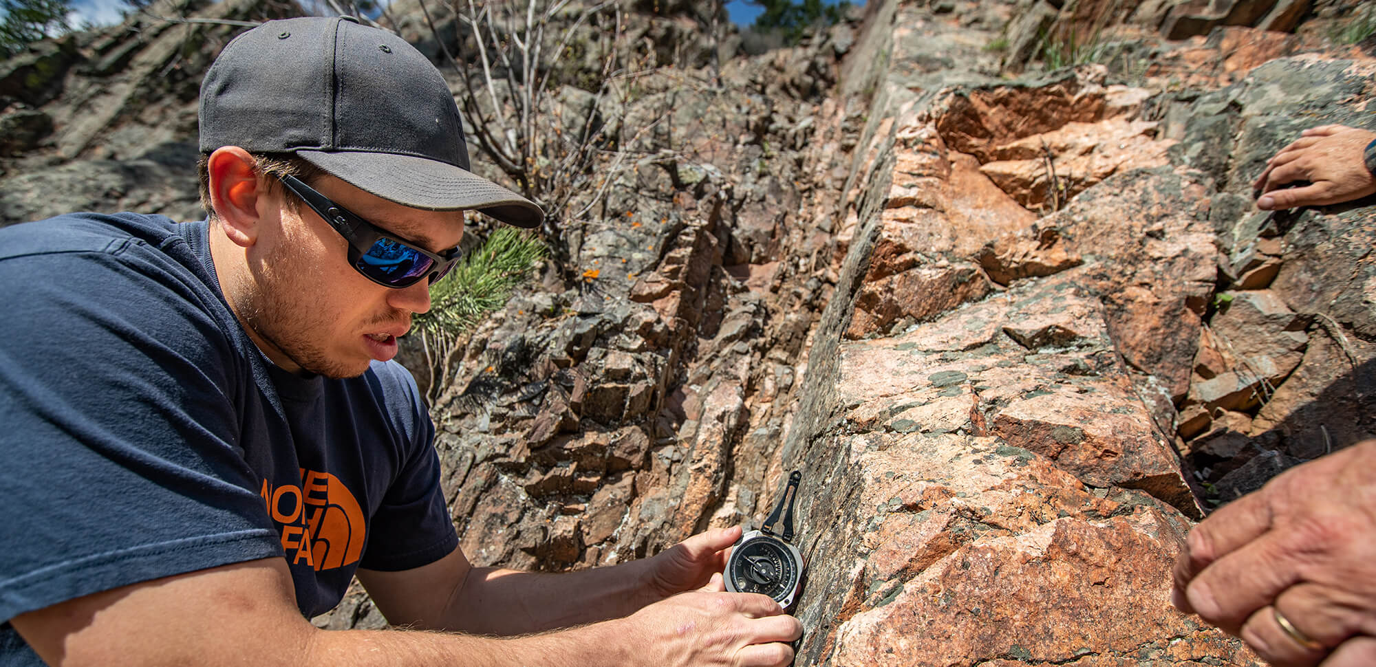 accounting-casper-college A student measures the angle of a rock formation outside.
