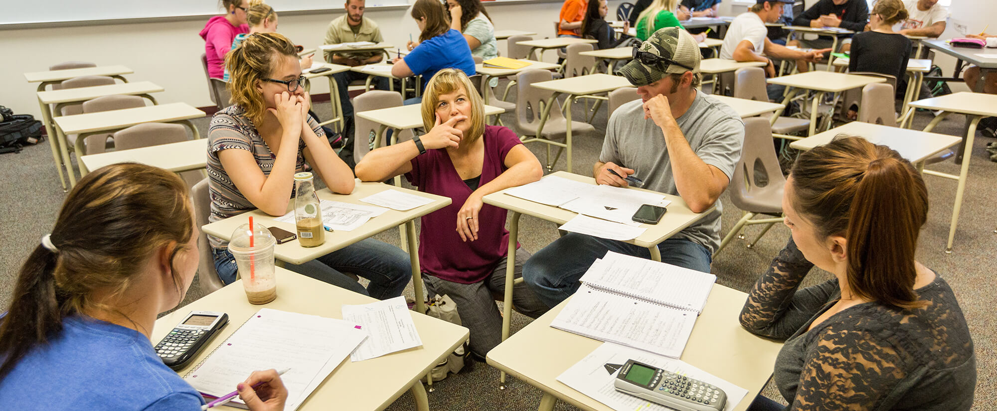 A group of math students receive help from their professor.