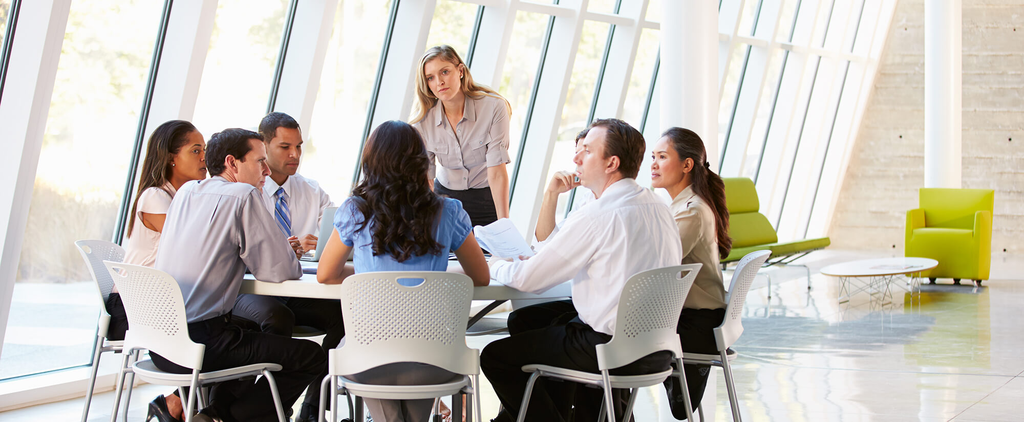 Photo of a group of business professionals at a round table in a contemporary office setting.