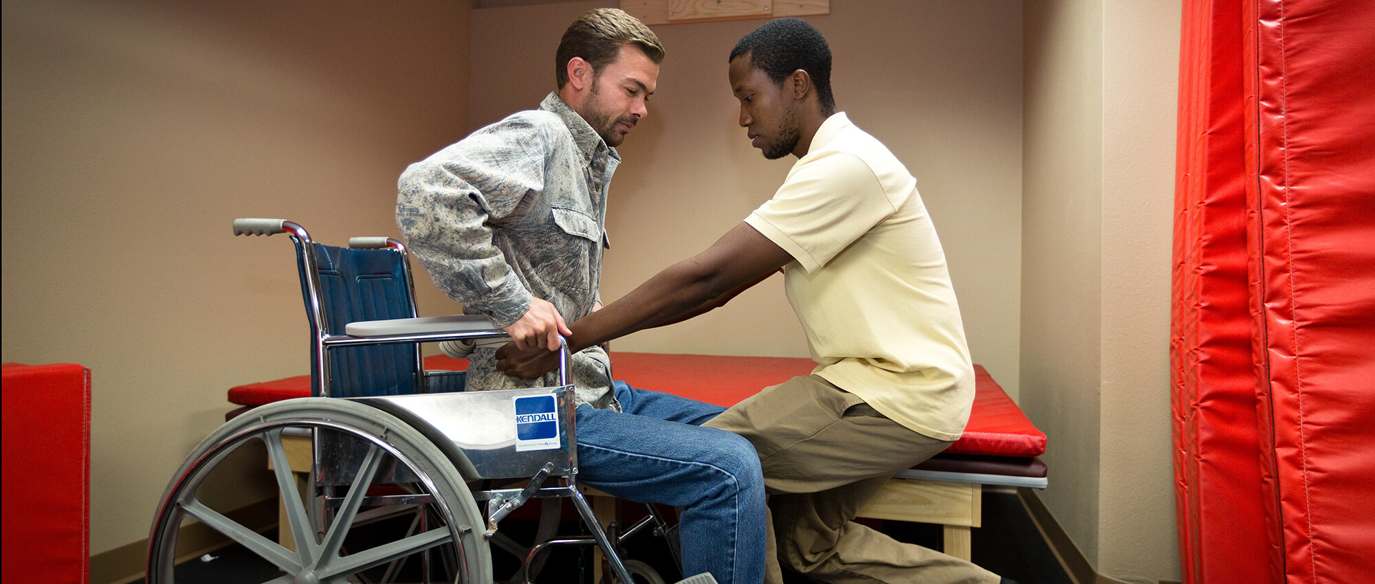 A student practices lifting another student out of a wheelchair.