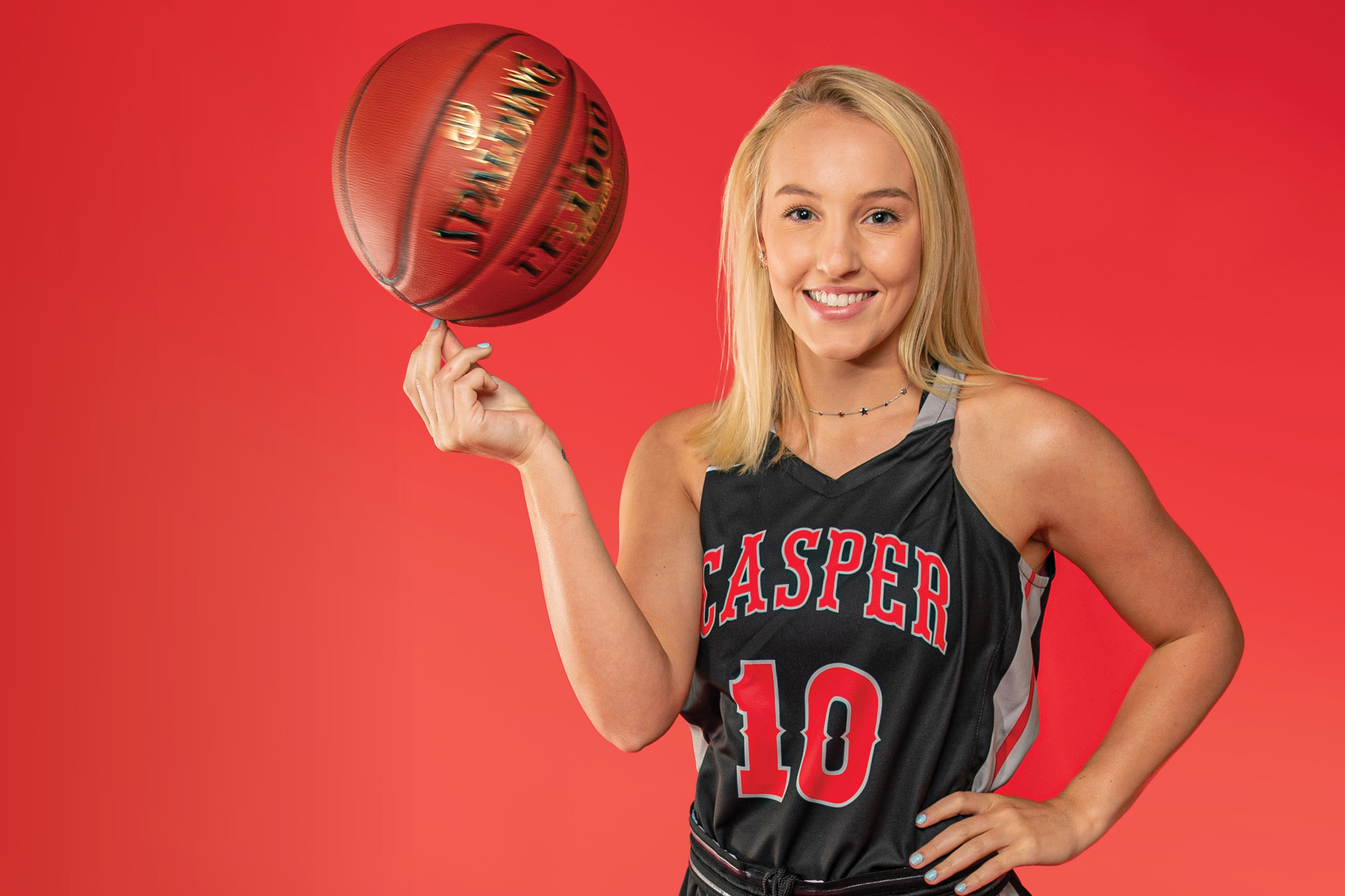 Photo of Casper College basketball player Bailey Johnson spinning a basketball on top of her fist.