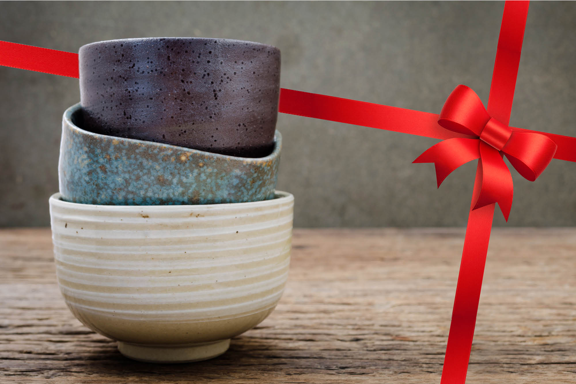 Photo of ceramic bowls with a red bow in the background.