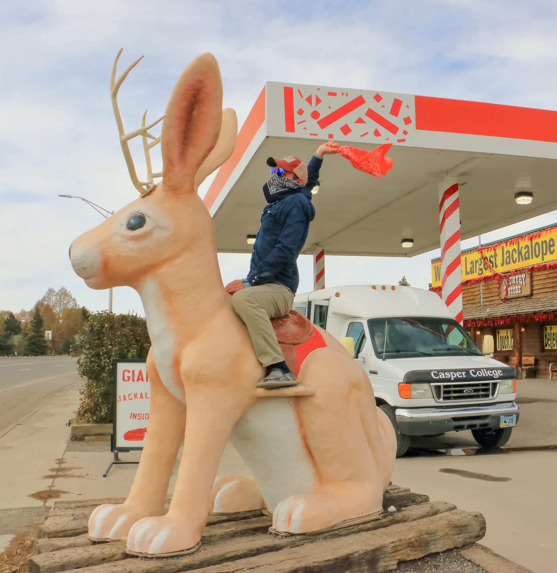 Student having fun posing on a statue of a jackalope