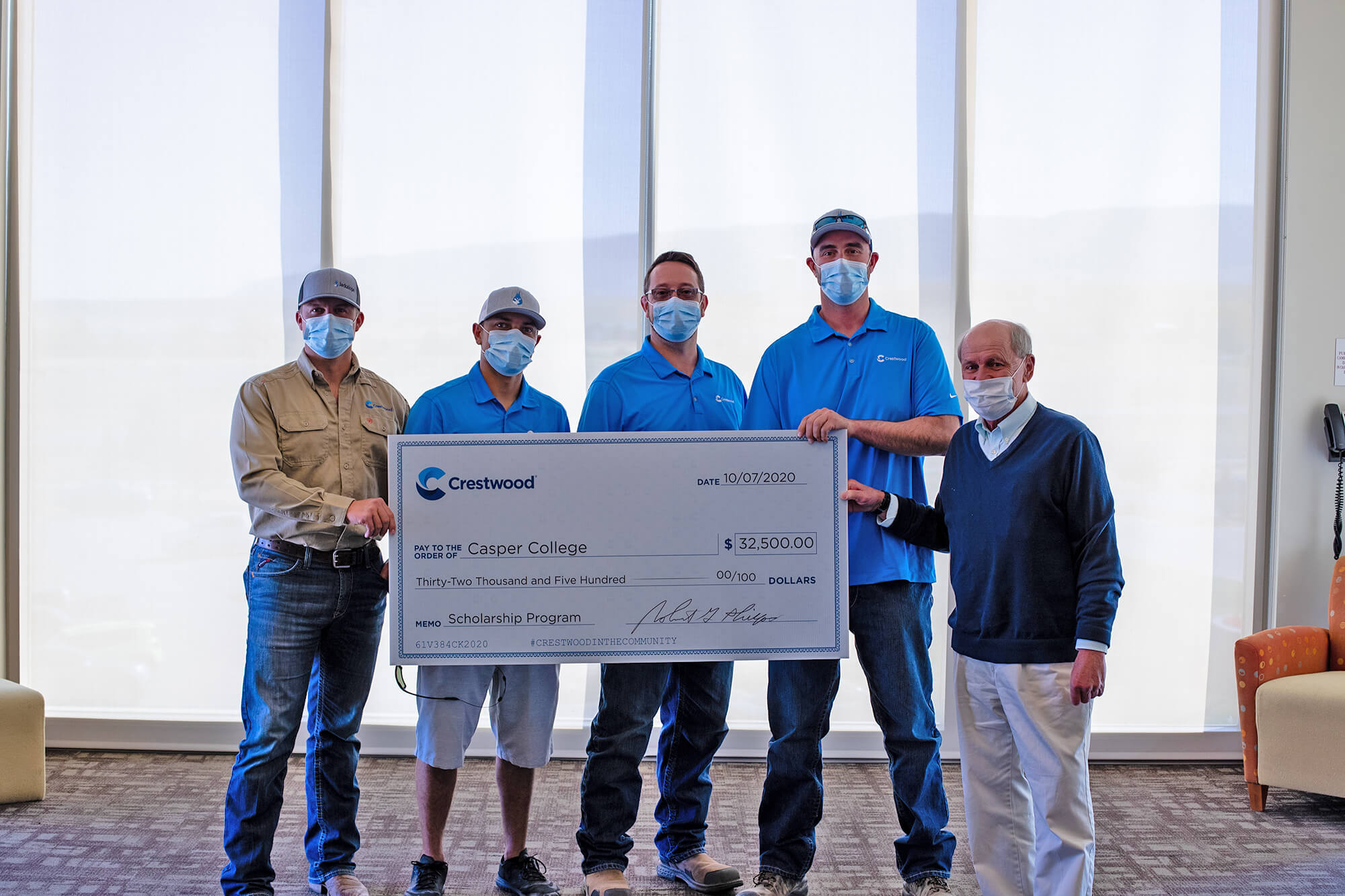 Photo of five men standing with a cardboard image of a check.