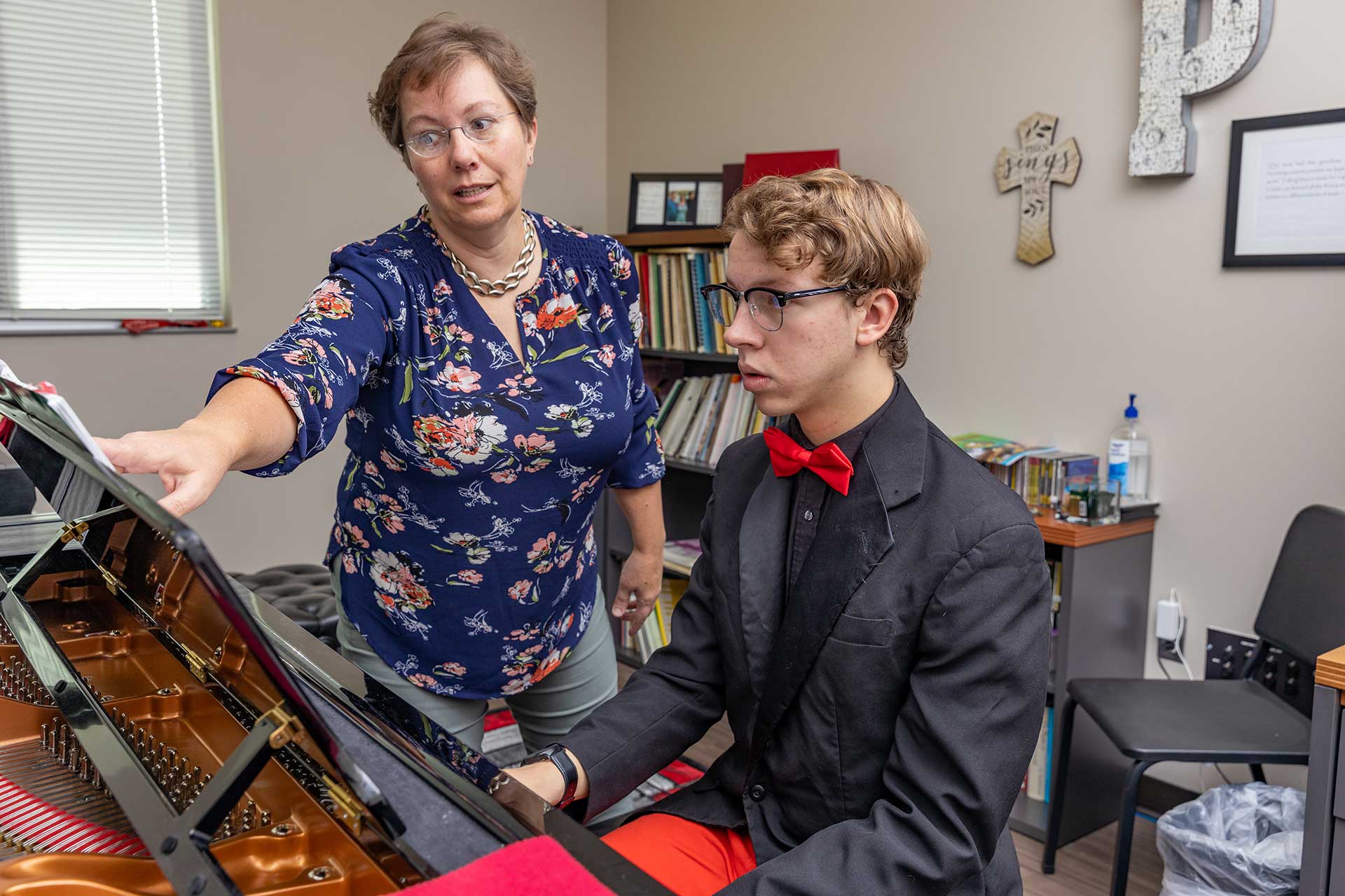 Casper College instructor gently adjust the handgrip of a student playing the violin.