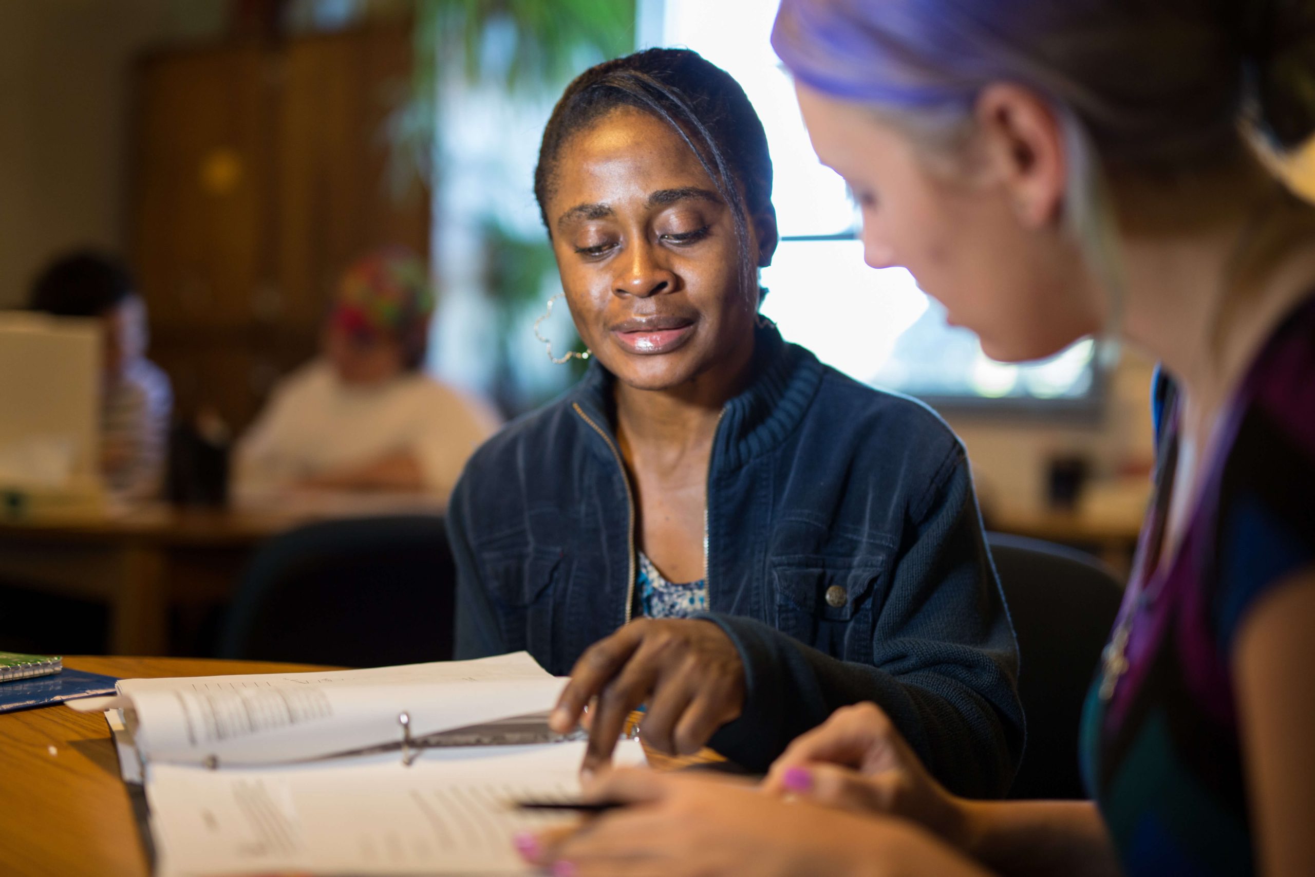 Photograph of a person helping another with a writing project.