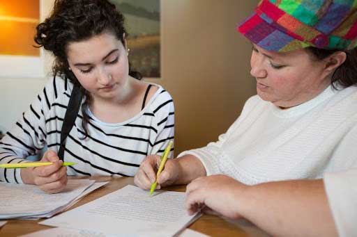 women in colorful hat tutoring a student