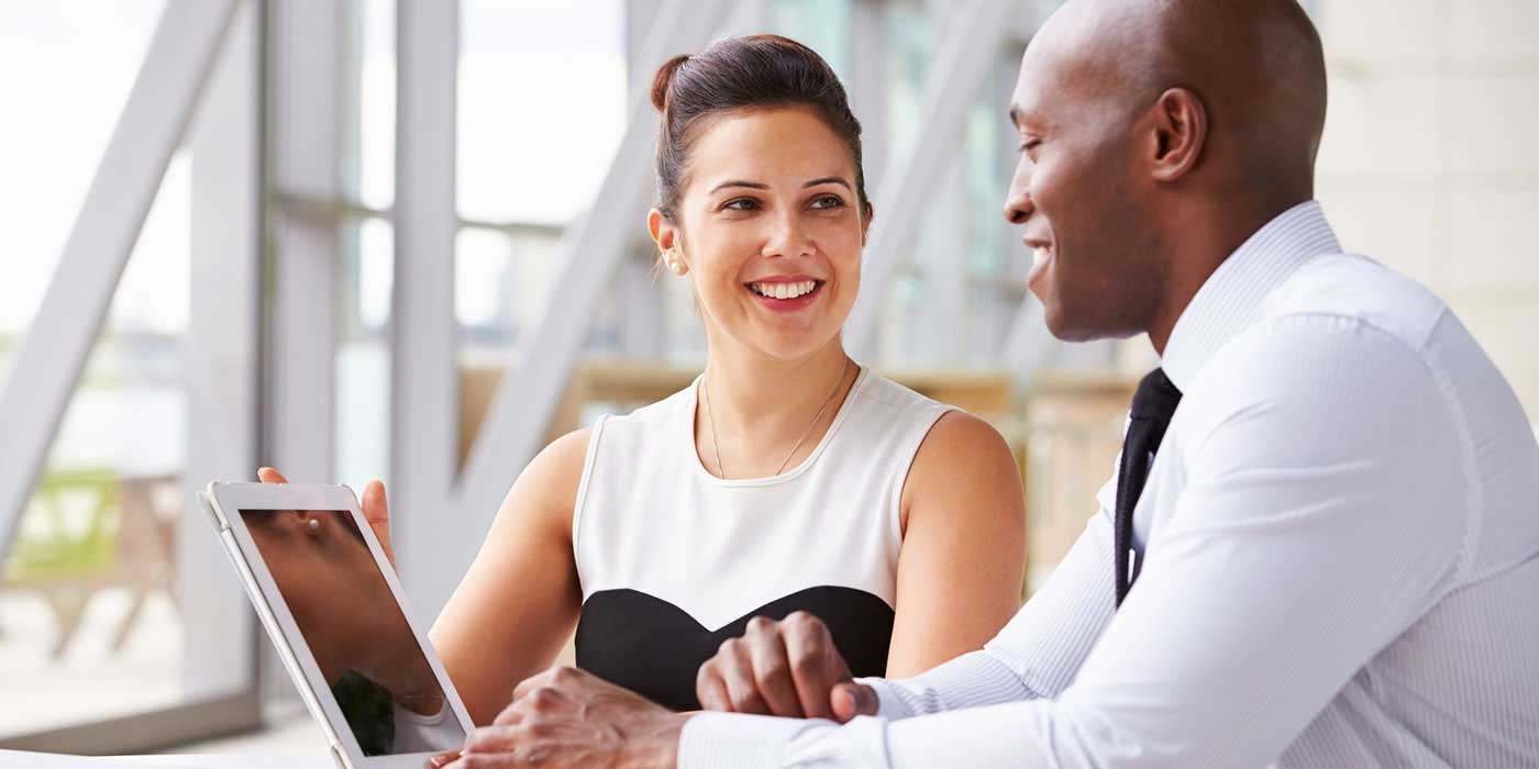 human resources photo of a man and women talking at a desk with a computer