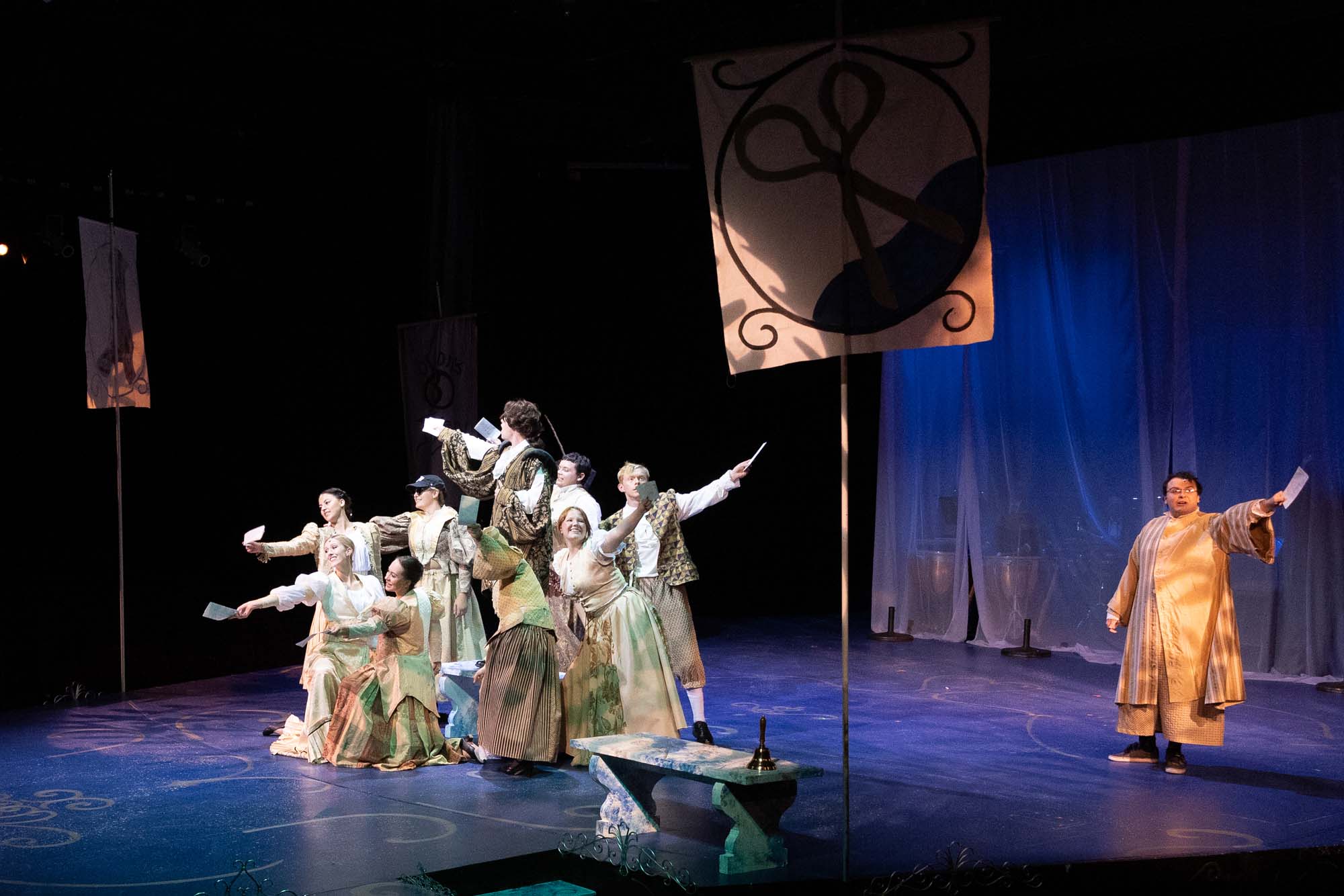 Students in greek costumes sing during a musical performance.