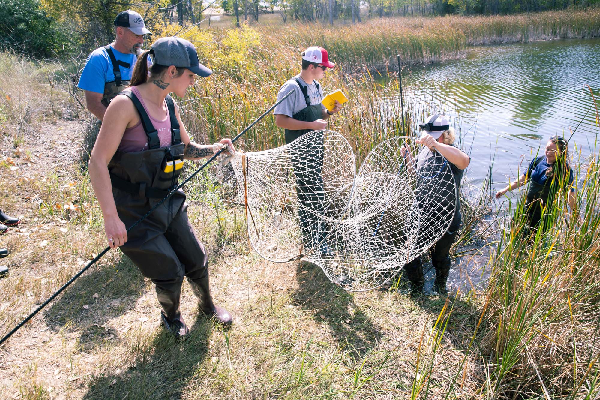 Students group around a tray of specimens collected in a stream on Casper Mountain.