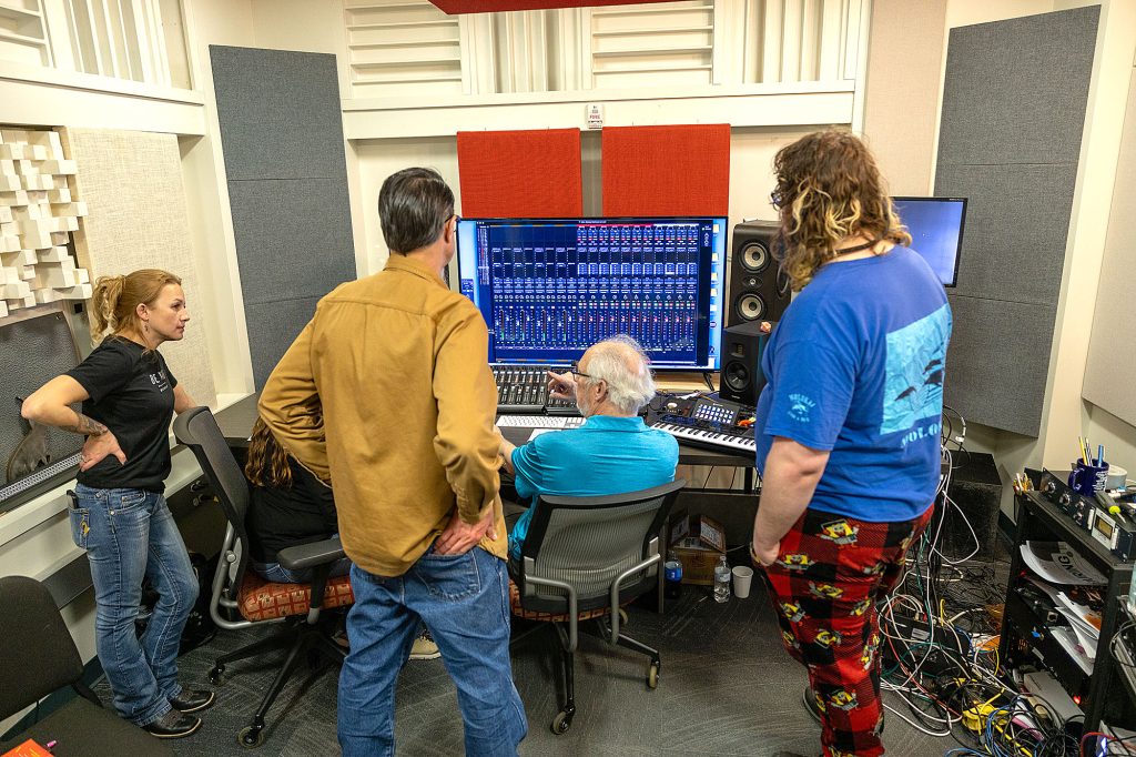 Photo of people looking at a large TV screen while participating in a recording session at Casper College.