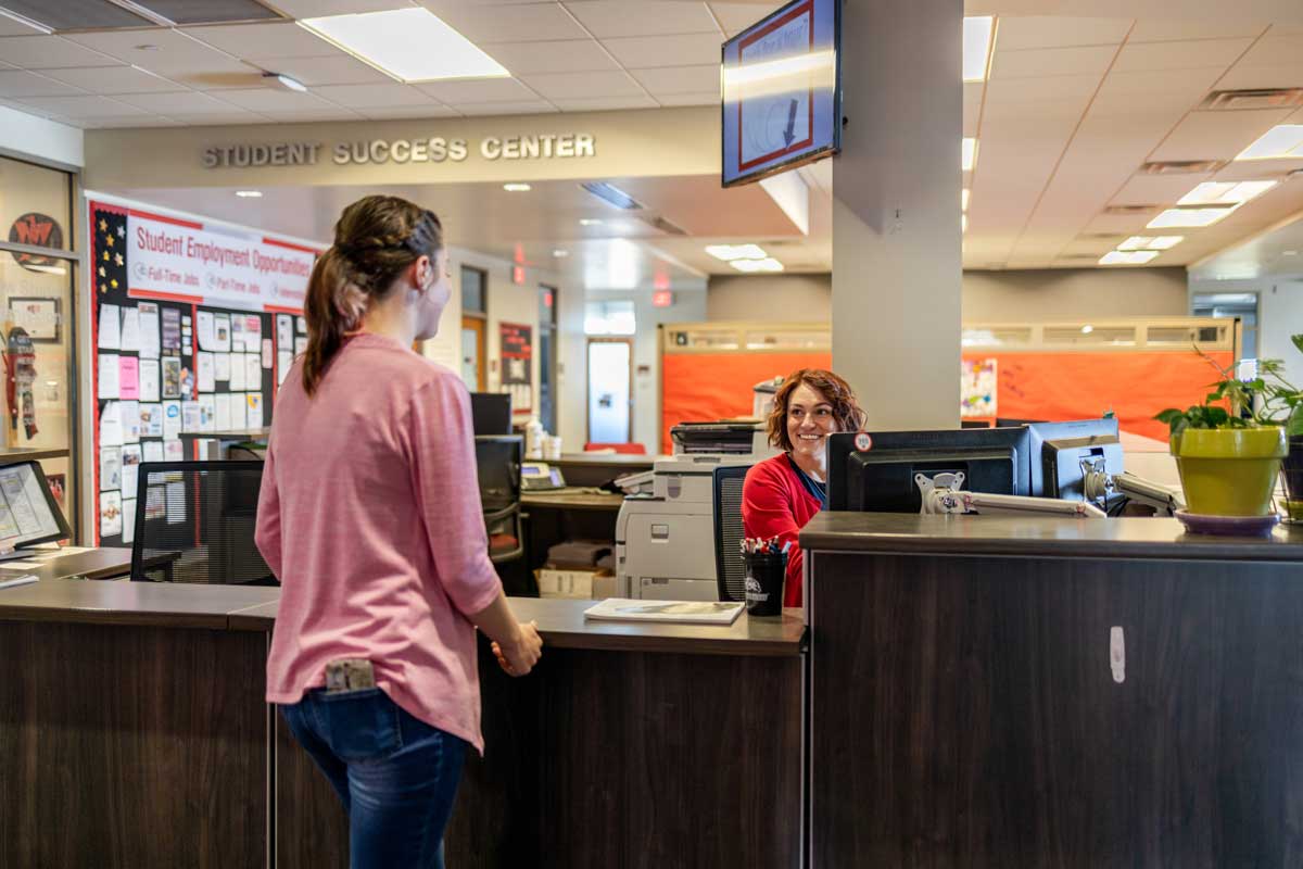 Two women talking at the entry way desk in the student success center