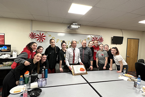 Photo of Casper College Women's Basketball team celebrating with Assistant Coach, Nate Macy, Head Coach Dwight Gunnare's 500th win in November 26, 2022.