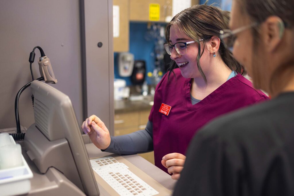Pharmacy technology student operates laboratory equipment while reviewing results with an instructor.