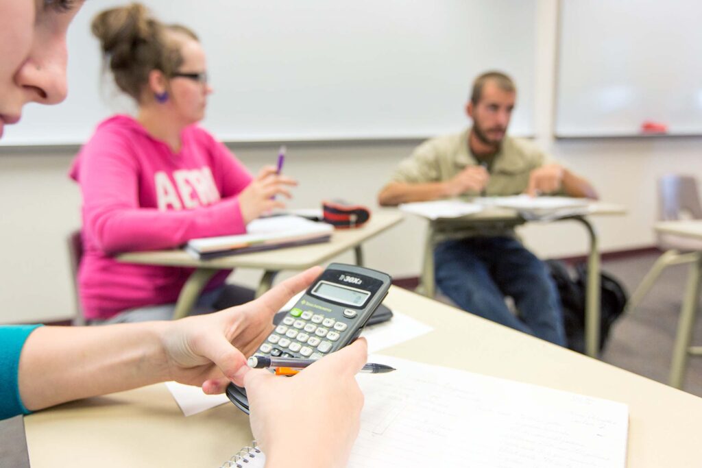 Students participate in a collaborative math class while using calculators and taking notes.