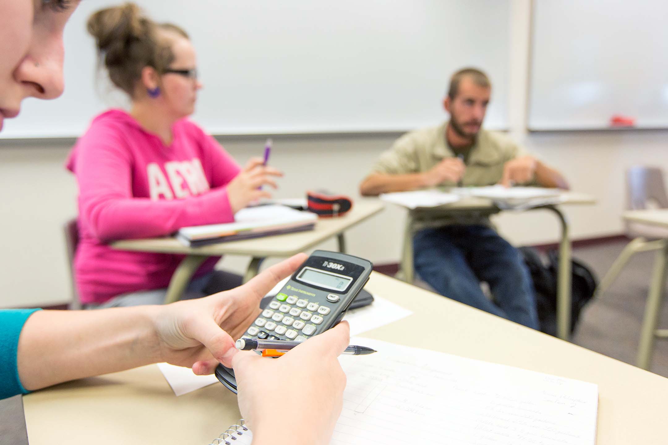 Students participate in a collaborative math class while using calculators and taking notes.