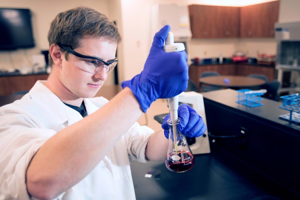 Medical laboratory technology student prepares and transfers a liquid sample with a micropipette in a science lab.