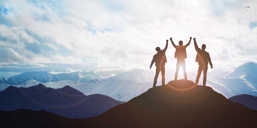 3 figures standing in victory on the top of a mountain