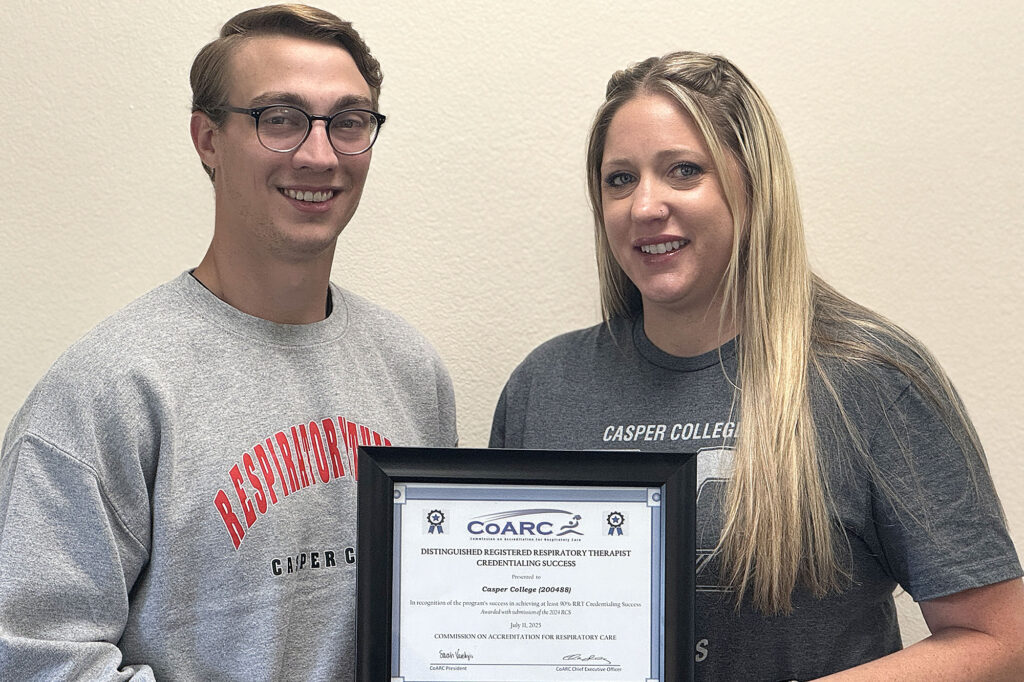 Photo of Grant Hosking and Tiffany Scott with a framed copy of the Distinguished RRT, registered respiratory therapist, Credentialing Success Award.