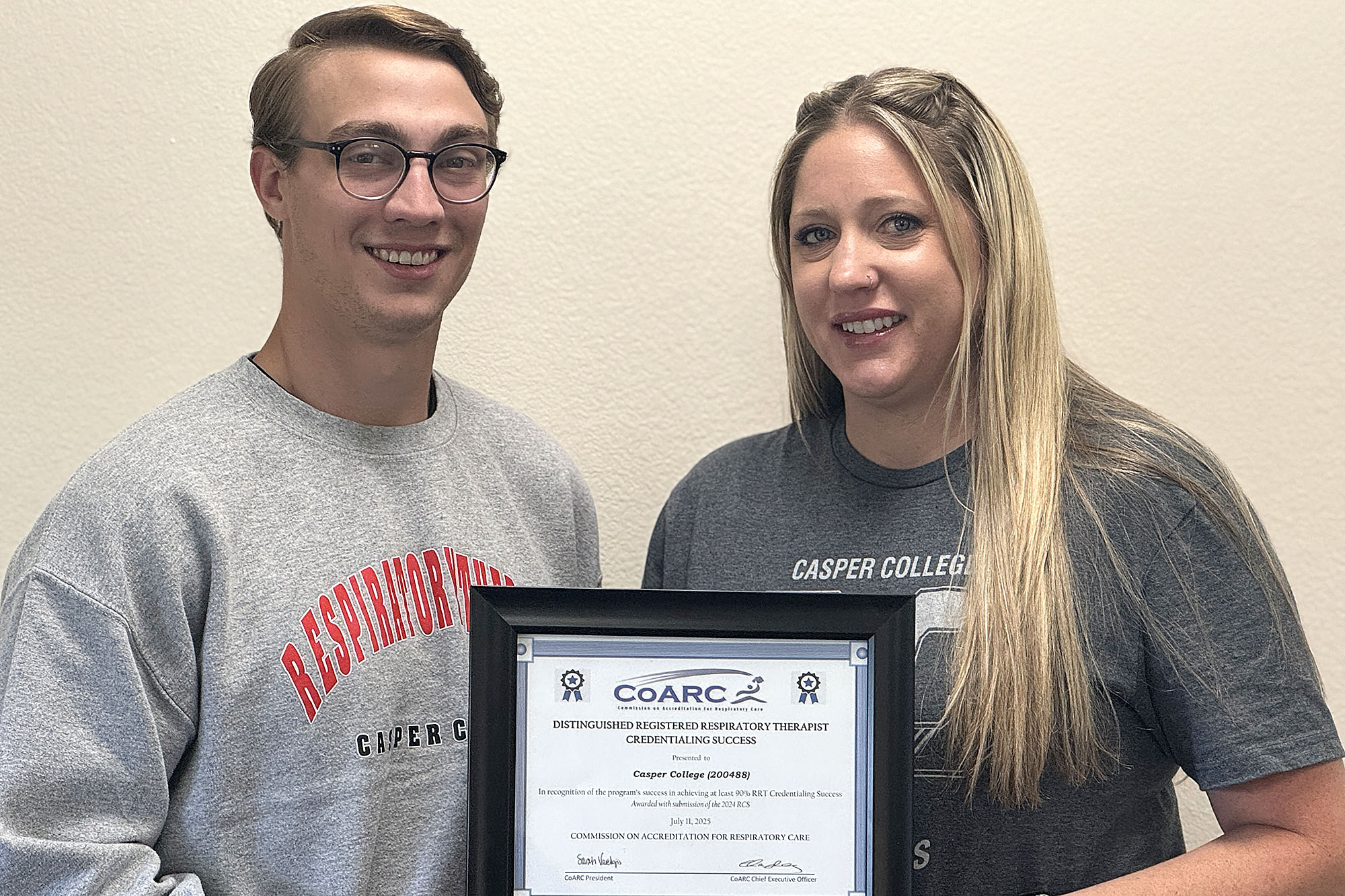 Photo of Grant Hosking and Tiffany Scott with a framed copy of the Distinguished RRT, registered respiratory therapist, Credentialing Success Award.