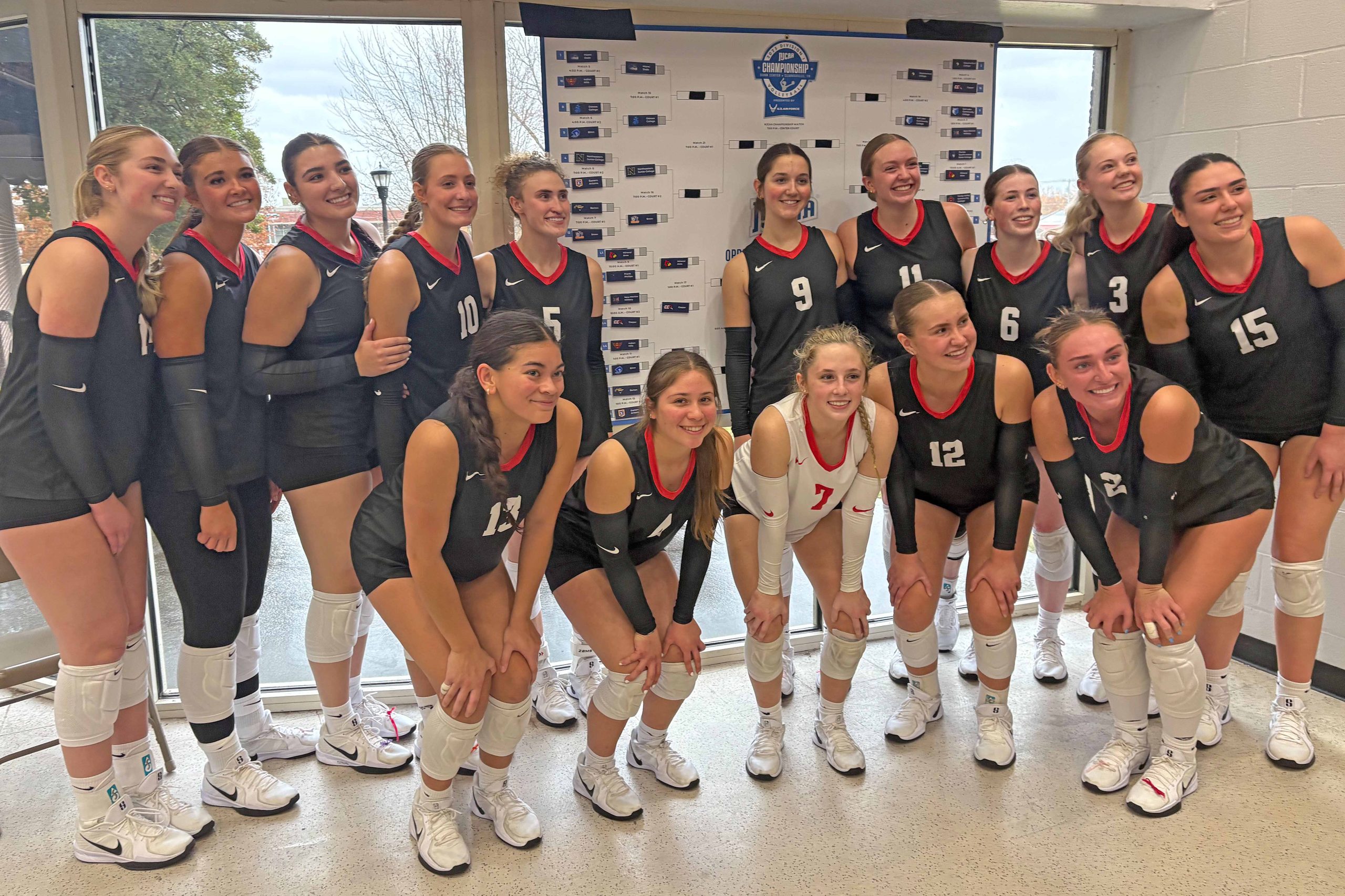 Photo of Casper College volleyball team at the 2025 National Tournament next to the leader board.