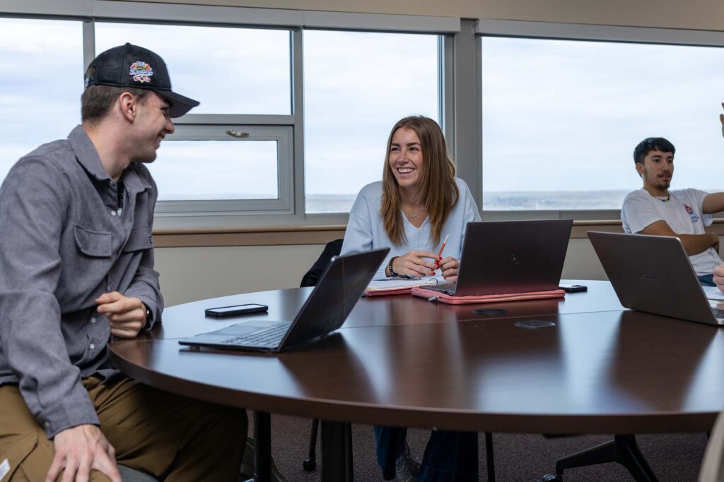 marketing students gathered around a table with labtops