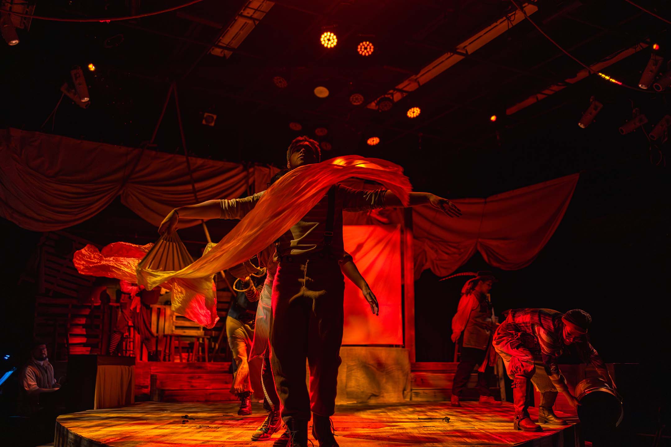 Actors perform a dramatic ensemble scene with flowing fabric and theatrical lighting during a Casper College theatre production.