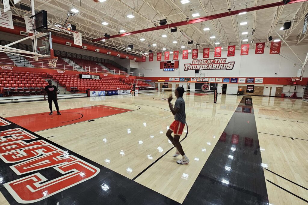 Person standing on a basketball court inside a large gymnasium. Athletic training