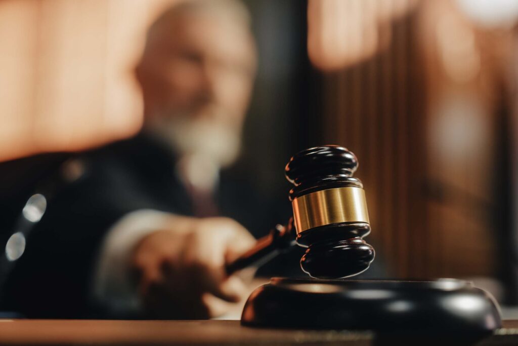 Judge’s gavel in the foreground with a blurred courtroom figure behind it. Criminal justice program header