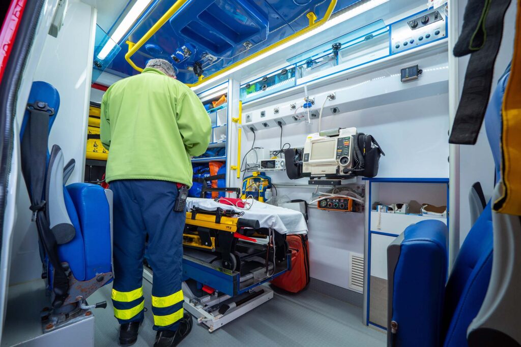 EMT standing inside the back of an ambulance surrounded by equipment.