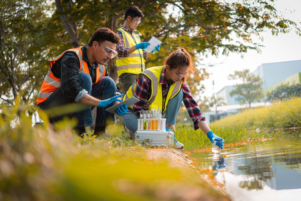 Group of students collecting water samples beside a pond. Environmental science