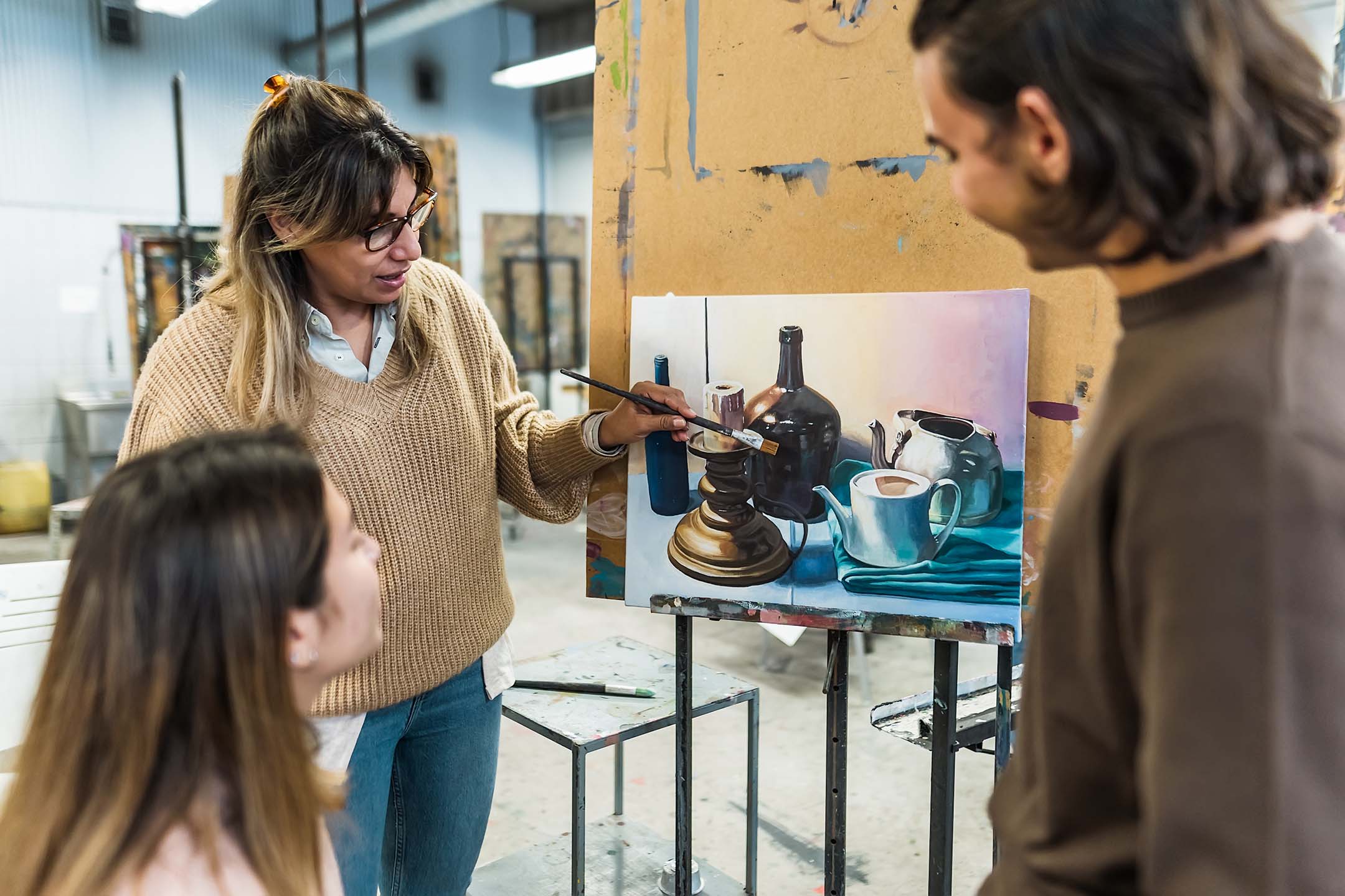 Art instructor speaking with students in a studio classroom.