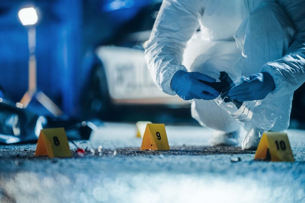 Investigator in protective gear collecting evidence markers at a crime scene. forensic science
