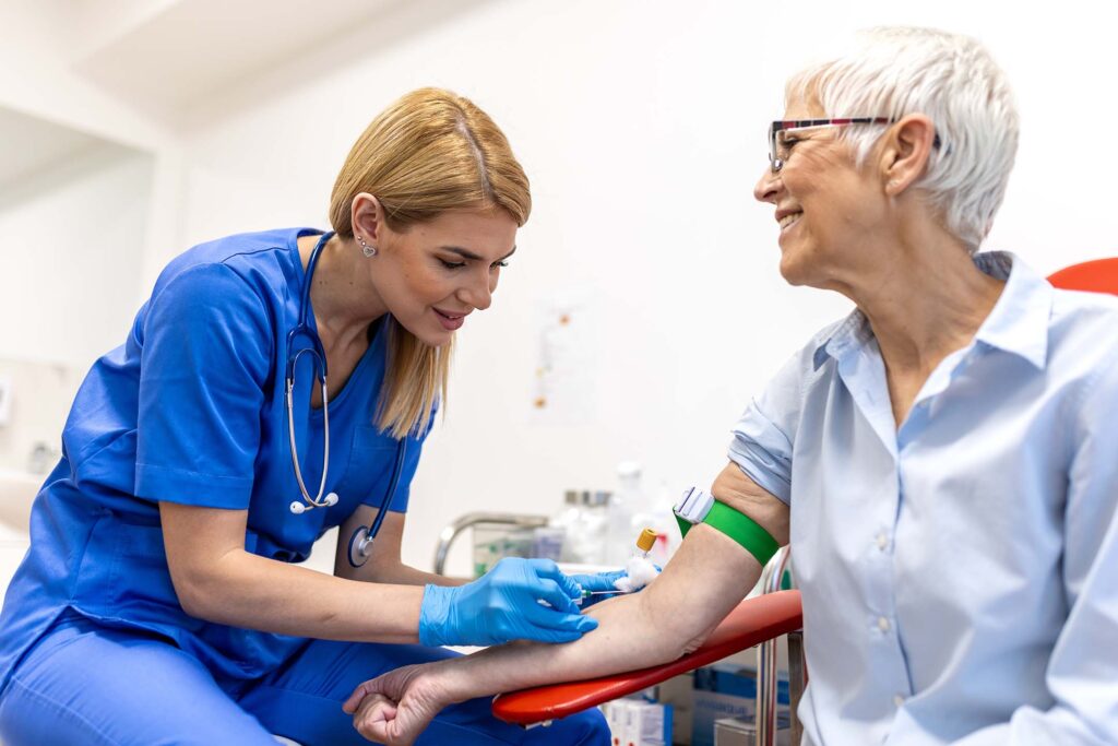 Healthcare worker drawing blood from an older adult. Medical laboratory technician