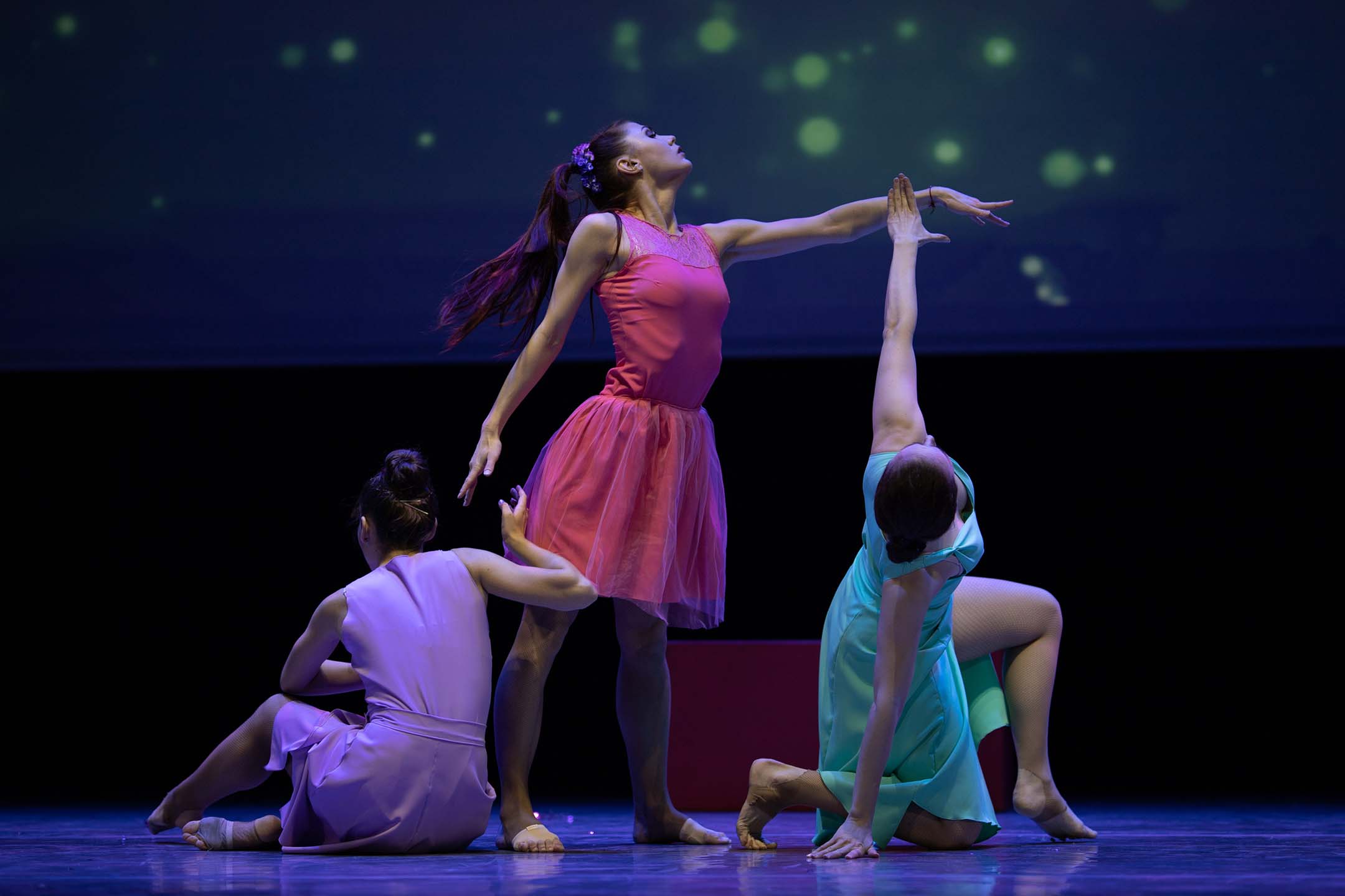 Performers dancing on stage under theatrical lighting for musical theatre.