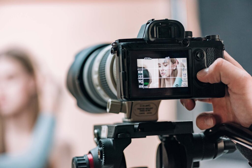 Close-up of a camera filming a person in the background. Photography
