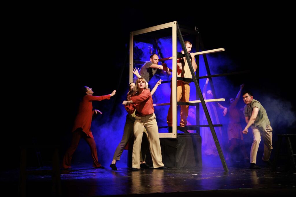 Theatre arts actors performing a dramatic scene with set pieces and colorful lighting.