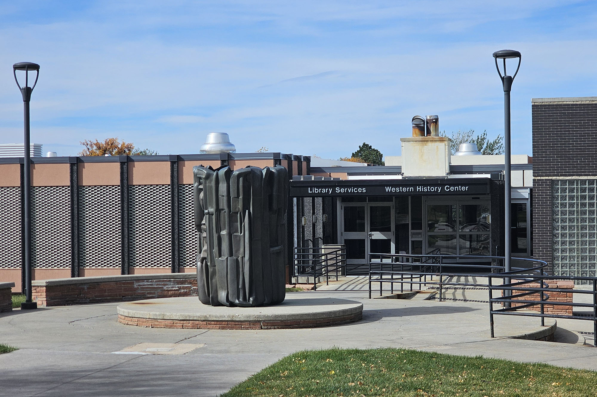 Exterior view of the Goodstein Foundation Library at Casper College featuring a large dark sculpture in the foreground. The building will now house the Casper College Testing Center.
